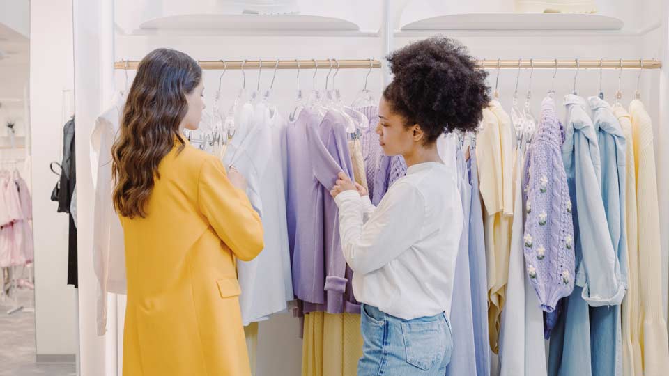 Two women in front of a clothes rack